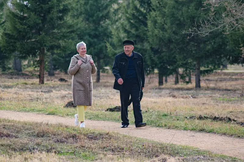 A smiling older couple walks along a sunny park path